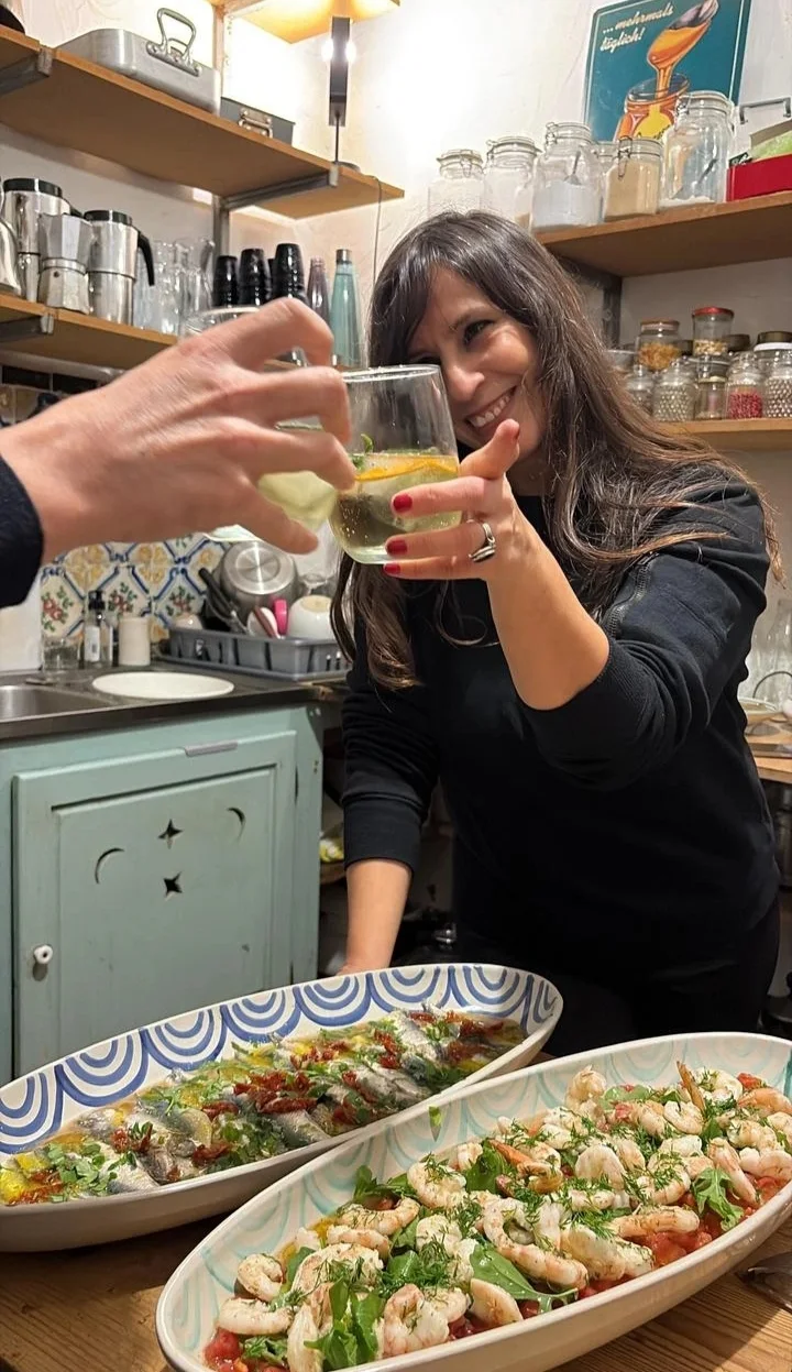 Nesrine Elamine sourit dans sa cuisine, derrière des plats préparés pour la table