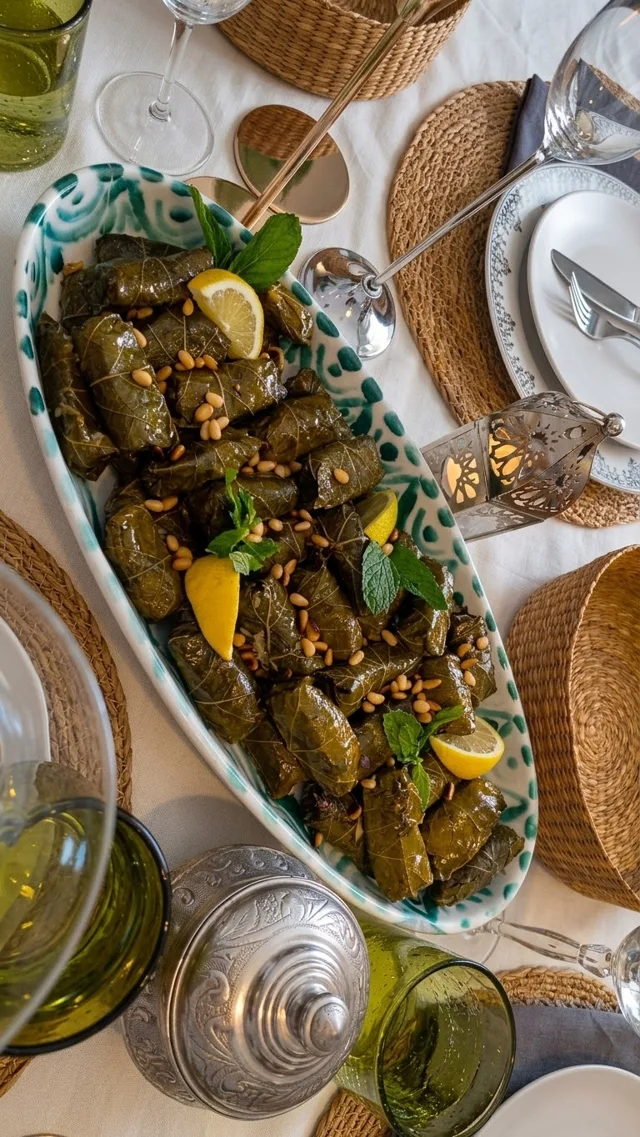 Feuilles de vigne présentées avec citron, menthe et pignons dans un plat en céramique